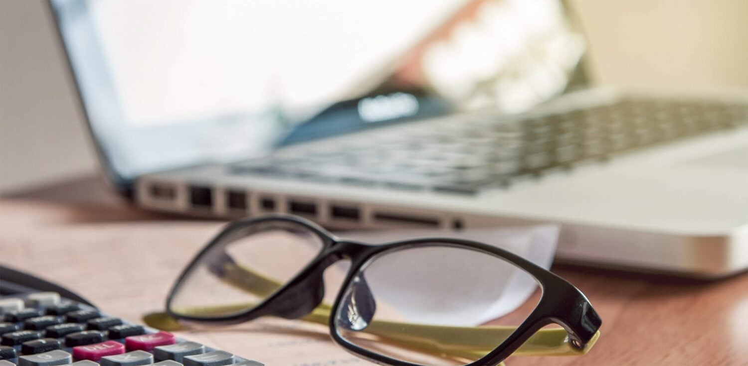pair of reading glasses next to an open laptop